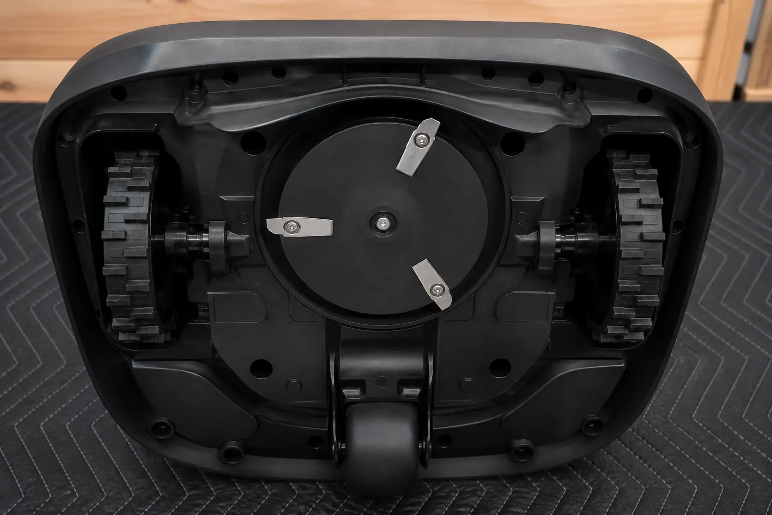 Clean underside of an unbranded robot mower with a small blade disc and three pivoting blades